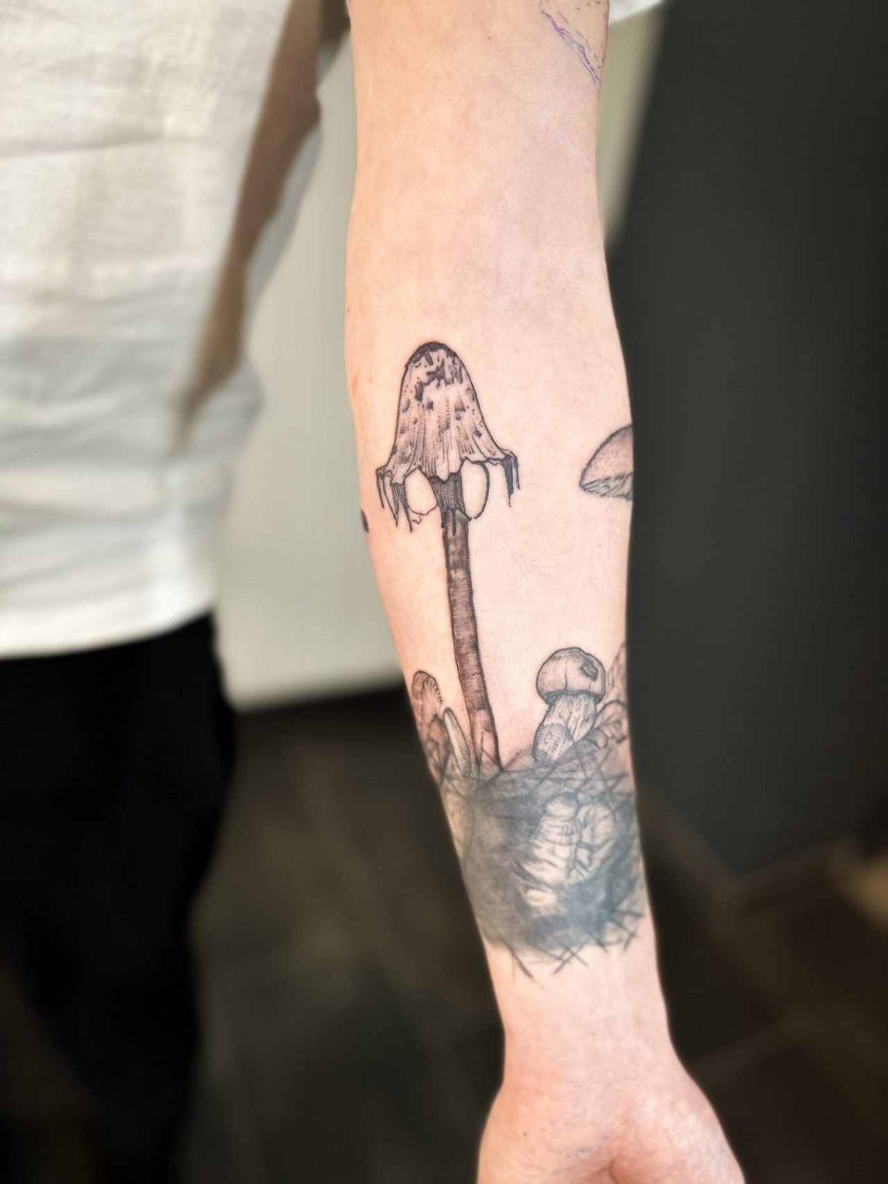 Armtattoo: Erdboden mit Knochen, Myzel und Pilz