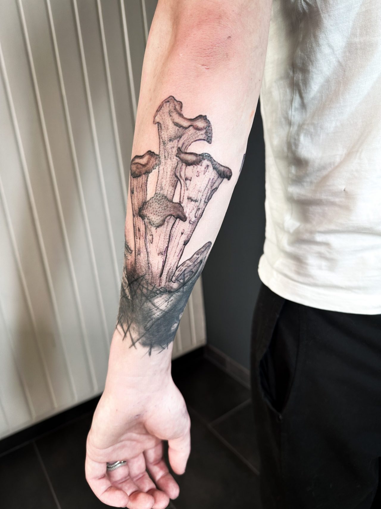 Armtattoo: Erdboden mit Knochen, Myzel und Pilz