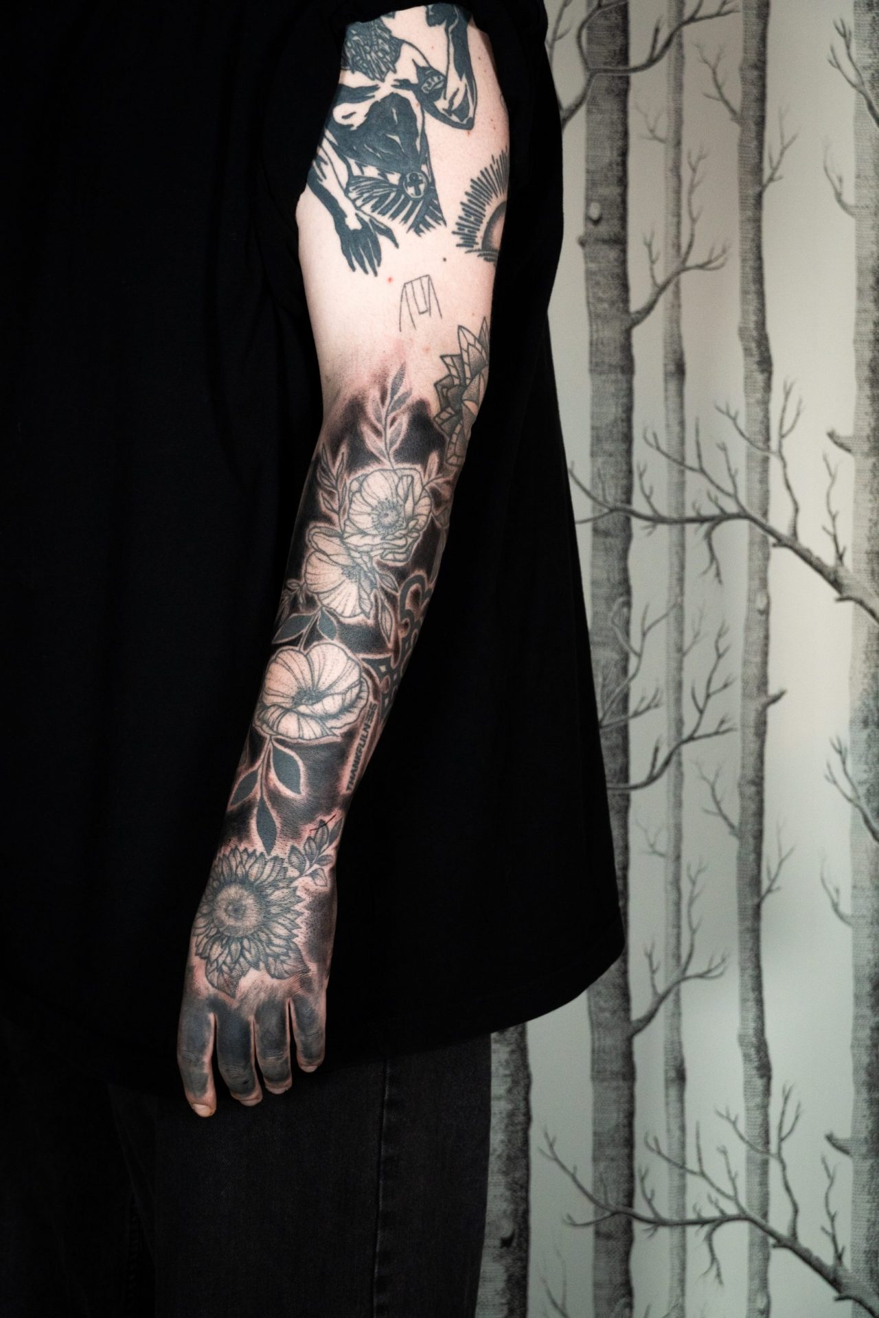 Armtattoo Blackout, vorhandene Blumenmotive werden umrundet und die Lücken schwarz ausgemalt