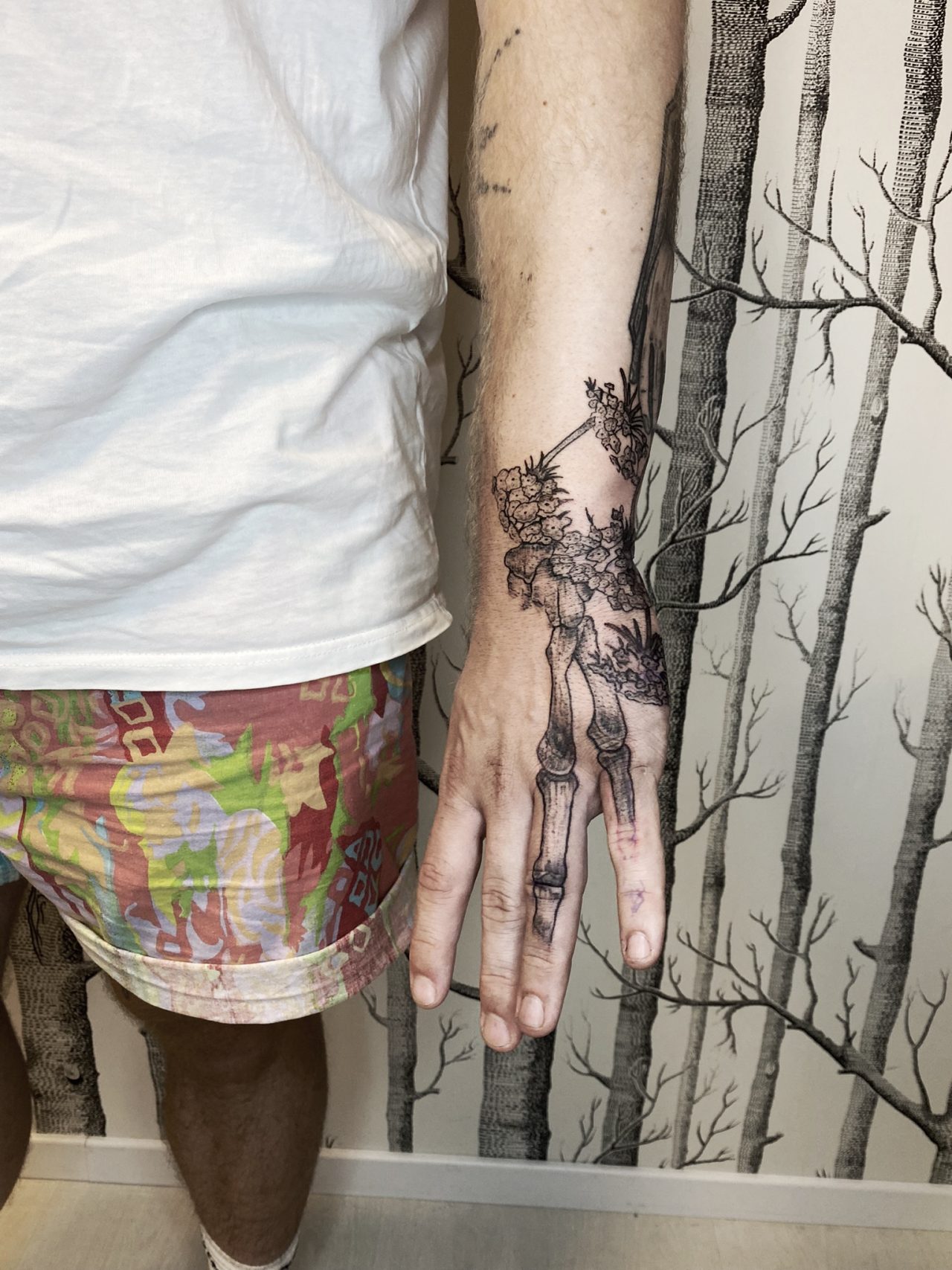 Handtattoo: nachgestellte Finger-Knochen bis zum Handgelenk mit Blüten