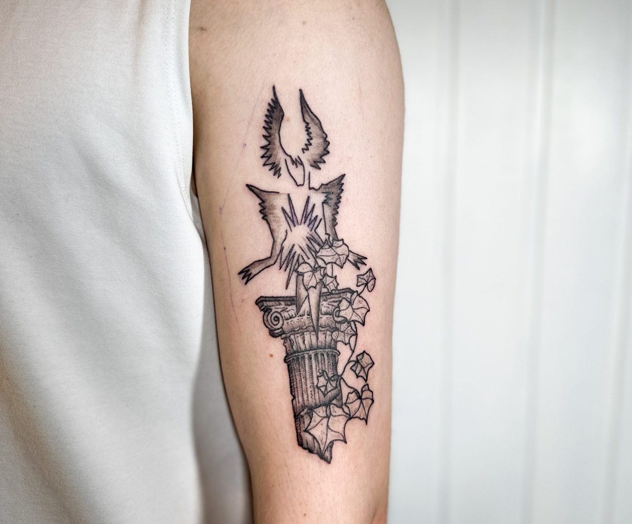 Armtattoo: Dragfigur auf antiker Stehle mit Efeuranke