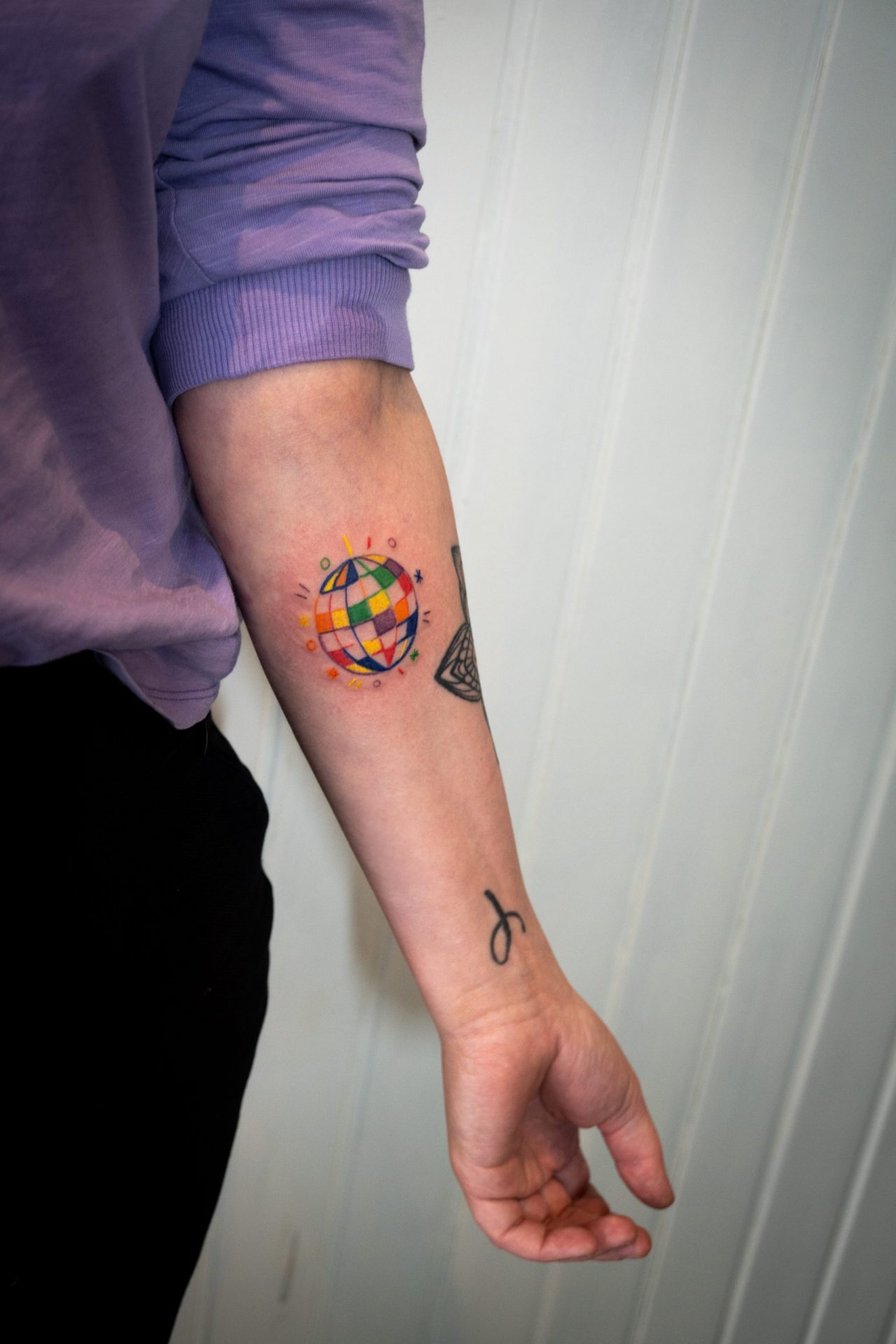 bunte Diskokugel mit Symbolen auf der Innenseite des Unterarms
