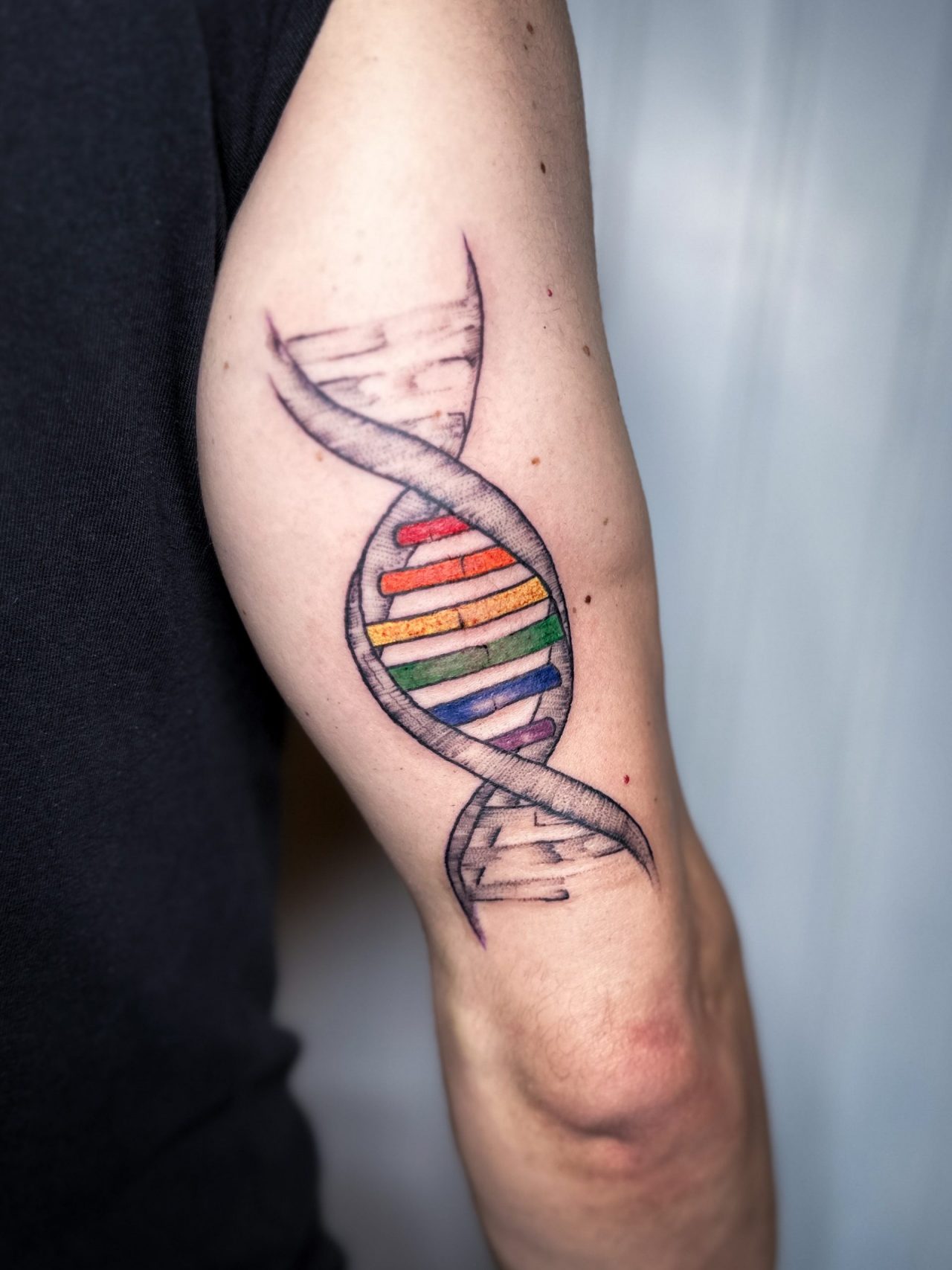 ein bunter DNA Strang auf der Oberarm-Rückseite