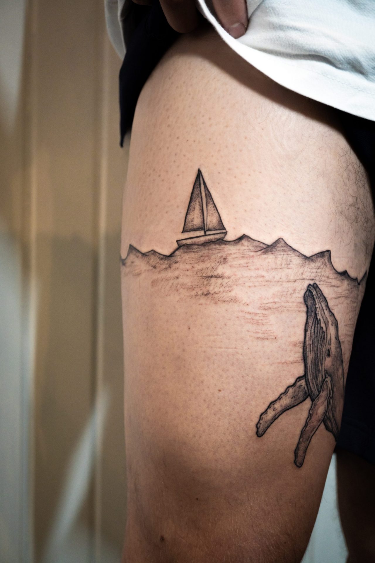 Oberschenkeltattoo: Wal unter Wasseroberfläche mit Boot