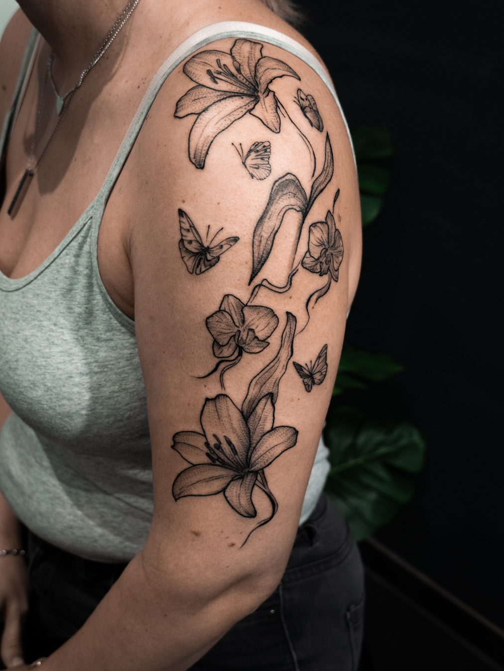 Matching Tattoo von Mutter und Tochter: Orchideen und Lilien fein verbunden mit Schmetterlingen auf dem Oberarm